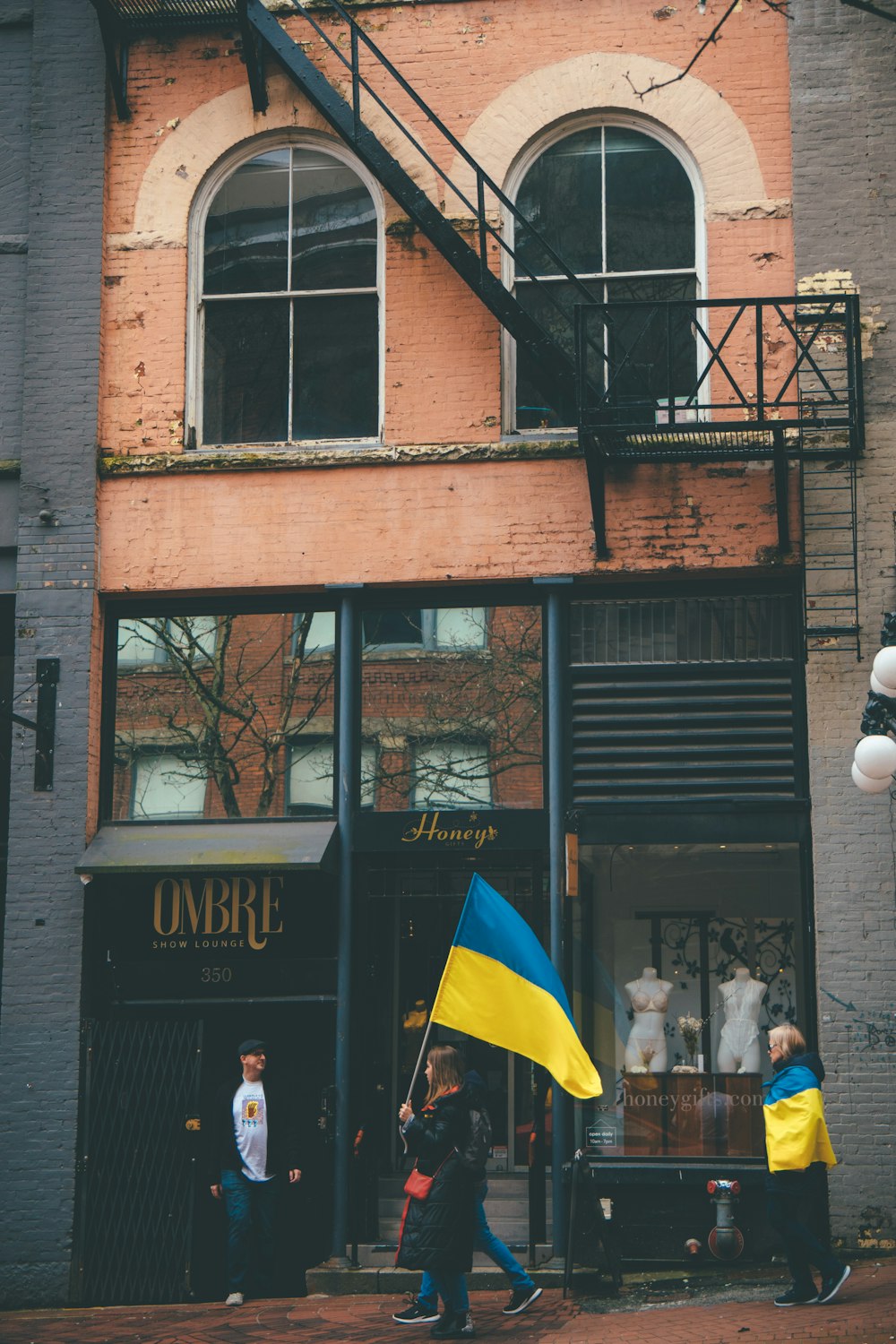 a group of people walking by a building with a flag