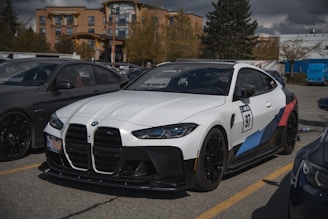 A sleek white and blue rental car parked near a busy airport terminal with travelers in the background.