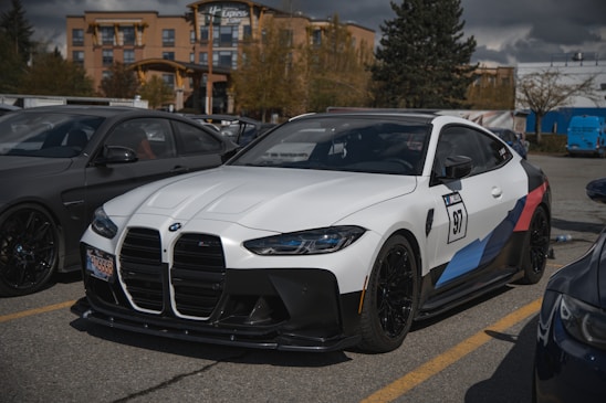 A sleek white and blue rental car parked near a busy airport terminal with travelers in the background.