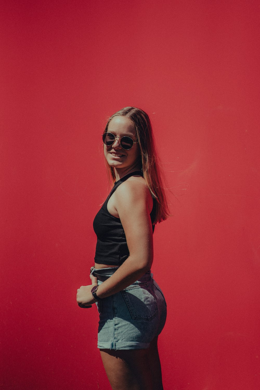 a woman posing in front of a red wall