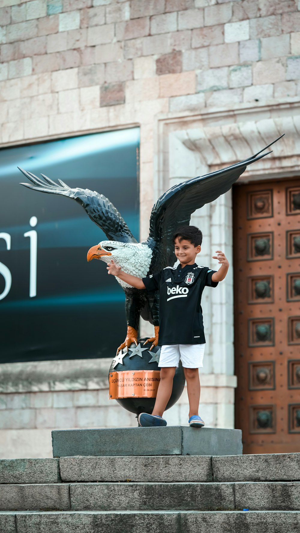a boy holding a large bird statue