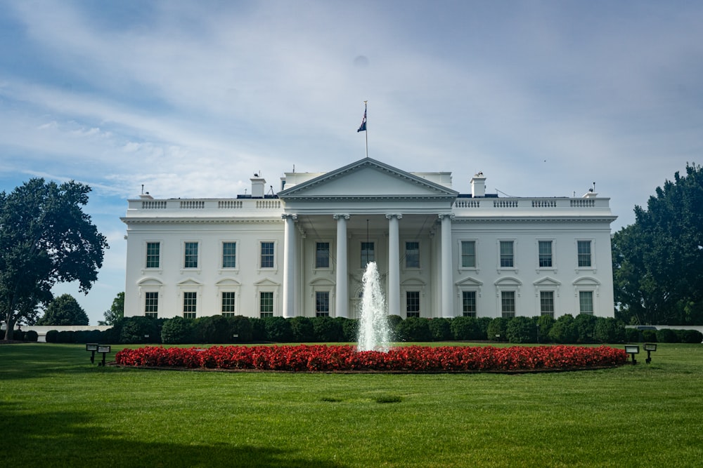 a white building with a fountain in front of it with White House in the background