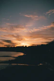 A serene sunset over a calm beach with silhouettes of people enjoying the view.