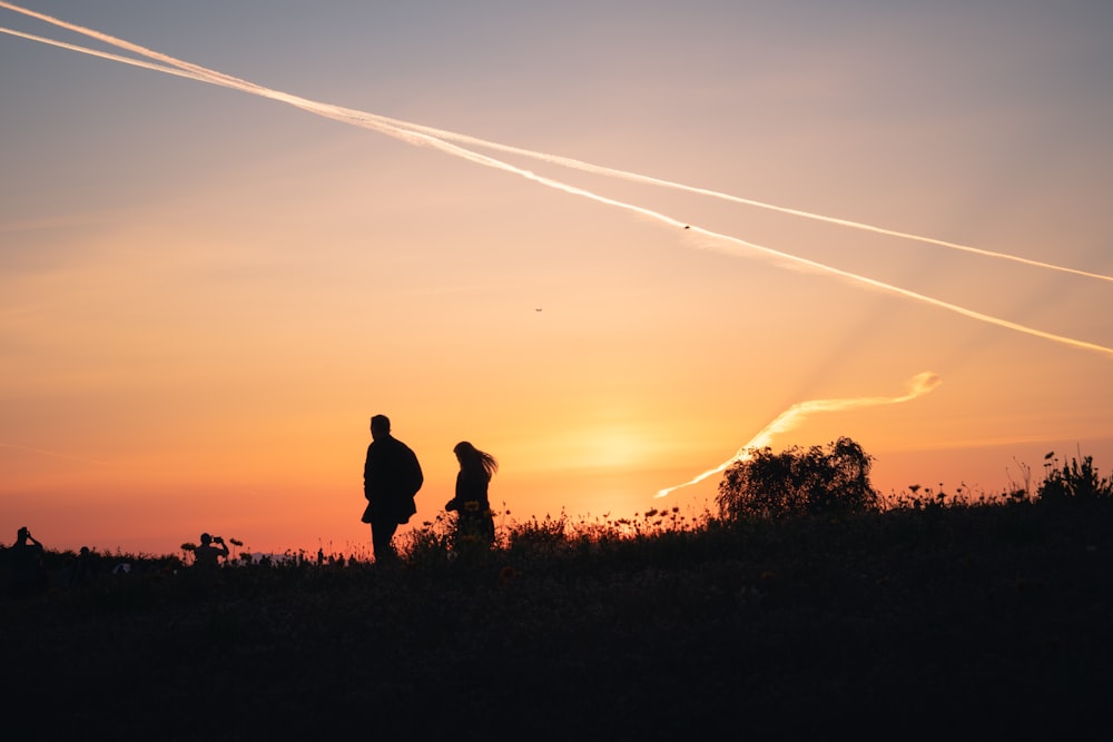 a couple of people standing in front of a sunset