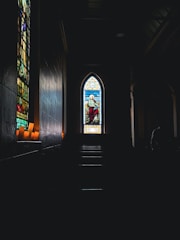 An old church with stained glass windows casting colorful light inside.