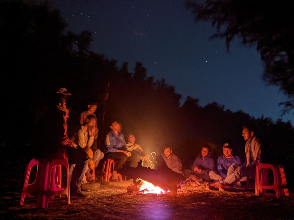 a group of people sitting around a fire at night
