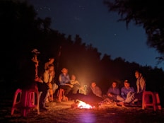a group of people sitting around a fire at night