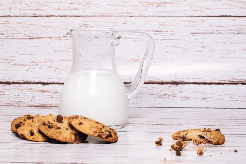 a glass of milk next to some cookies and a couple of bananas