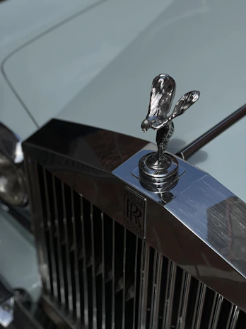 A close-up shot of a Rolls-Royce Phantom’s iconic grille and Spirit of Ecstasy hood ornament, emphasizing craftsmanship.