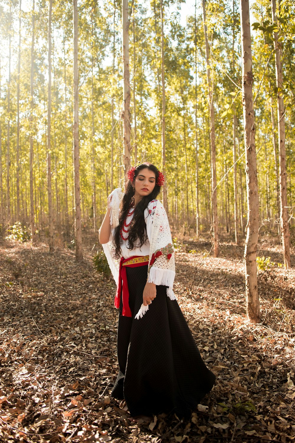 a woman in a dress standing in a forest