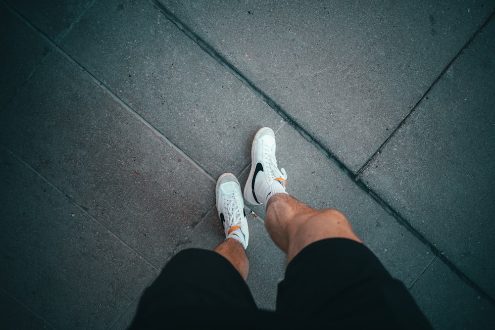 a person's feet in white shoes on a grey surface