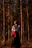 Portrait of a smiling tribal woman in traditional attire standing in a sunlit forest clearing