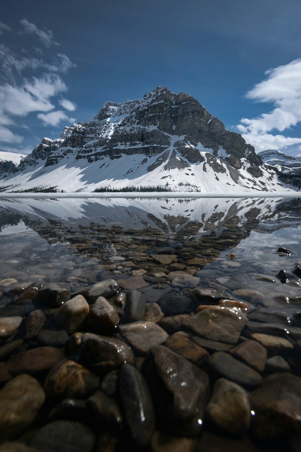 a snowy mountain with rocks and water