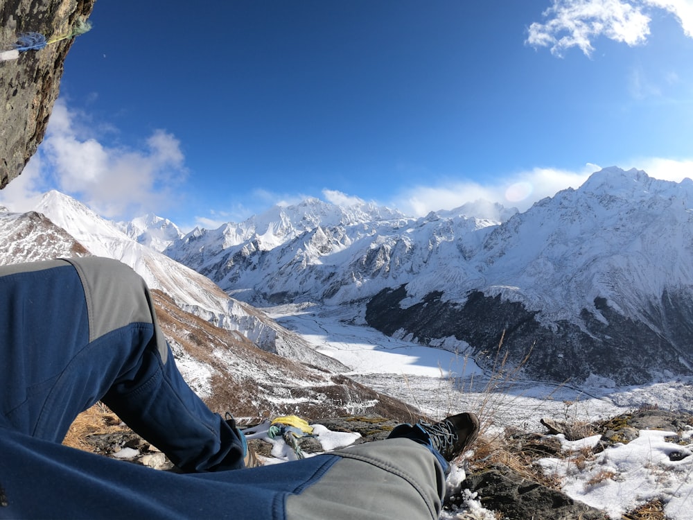 a person sitting on a rock looking at a snowy mountain range