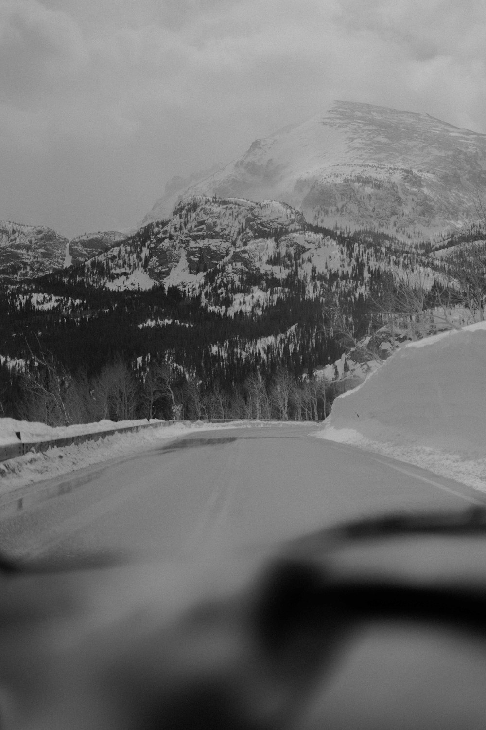 a road with snow on the side and mountains in the background