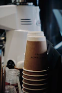 Stacked coffee cups and pastry boxes ready for pickup.