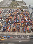 Close-up of hands coordinating shipping documents with a backdrop of a container yard and ships.