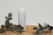 Soft foam cleanser in a matte black tube resting on a dark stone surface with natural leaves nearby