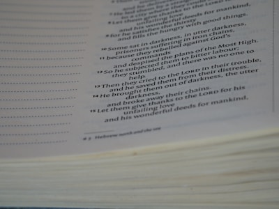 A close-up view of an open book with text focused on religious or biblical content. The visible lines of text are clear and legible, set on an off-white page with a noticeable thickness on the page edges.