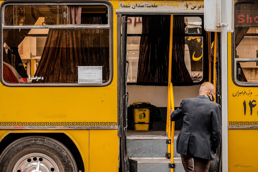 a person stands in front of a yellow bus