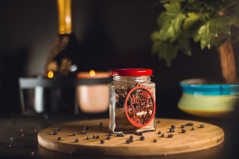 a glass jar with a red lid and a white candle in it