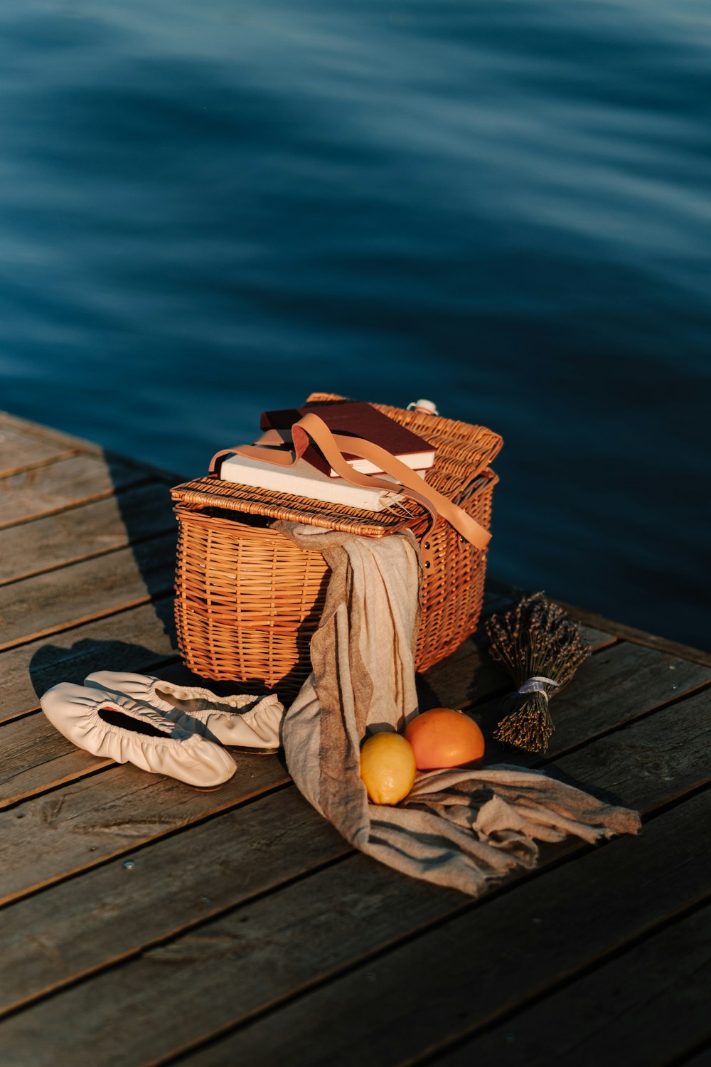 a basket and some fruit on a dock by the water