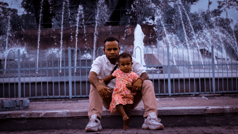 a person and a child sitting in front of a fountain