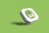A three-dimensional icon with a green circular background and a white border, featuring a white compass or drafting tool at the center. The icon casts a slight shadow against a light green background.