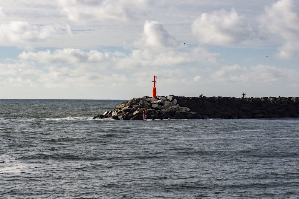 a rocky island with a red light house on it