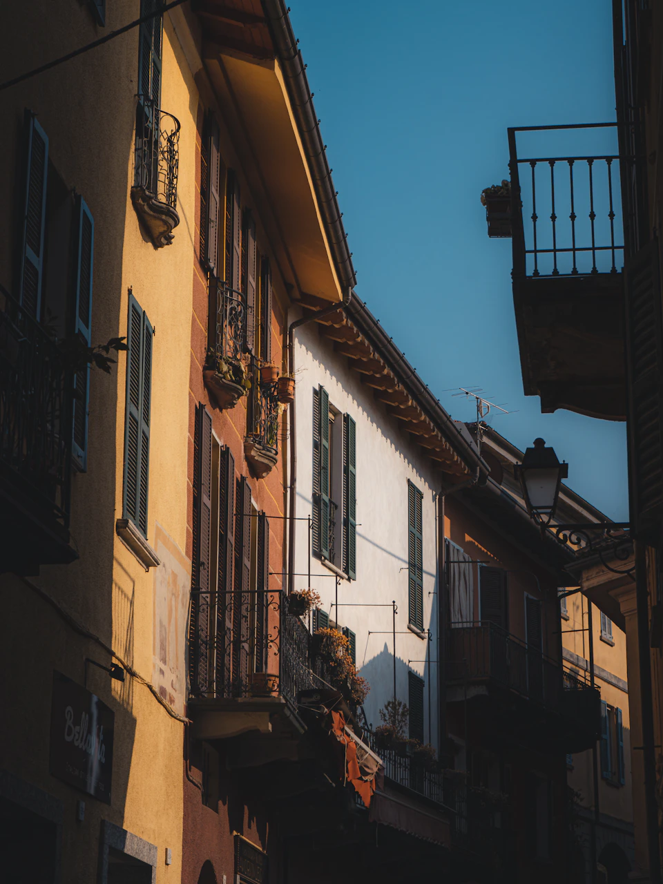 Narrow street lined with old buildings featuring balconies and colorful window decorations outdoors