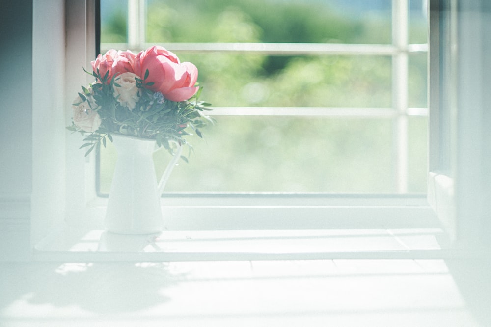 a vase with flowers on a window sill