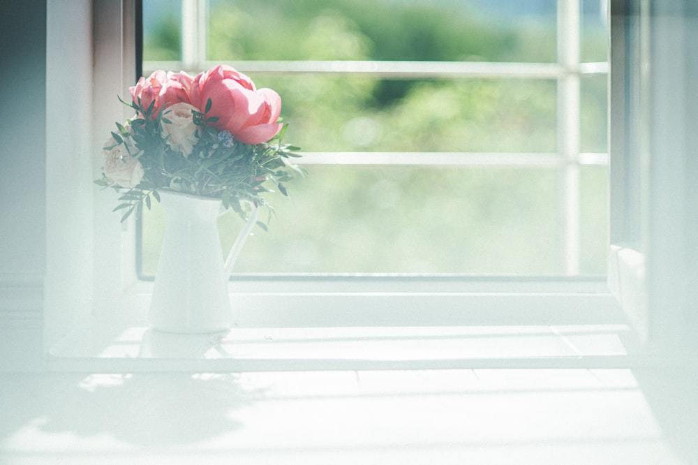 un vase avec des fleurs sur un rebord de fenêtre