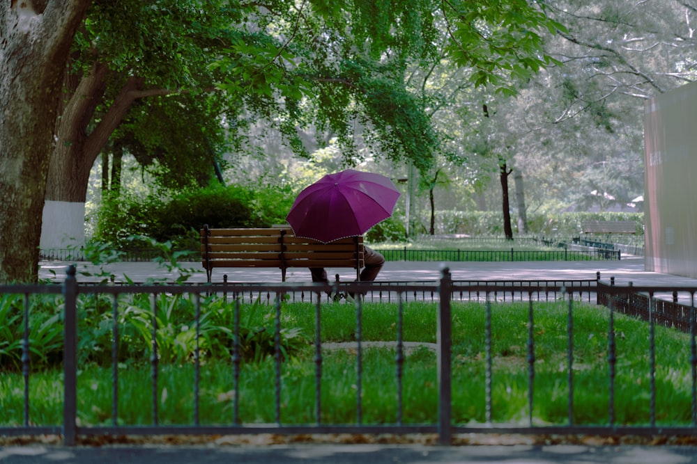 Eine Person, die auf einer Bank unter einem Regenschirm sitzt