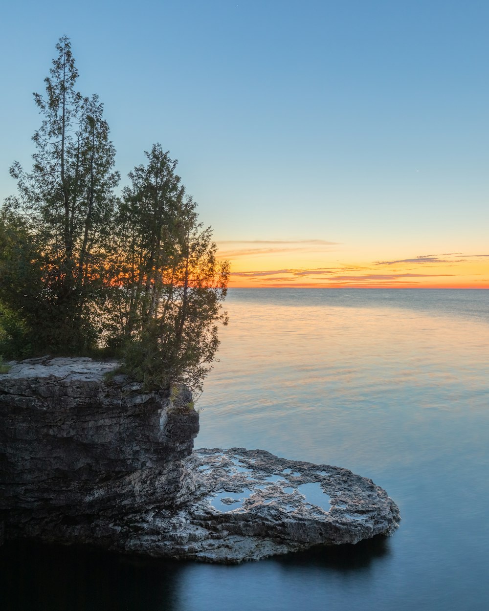 uno specchio d'acqua con alberi e rocce sul lato