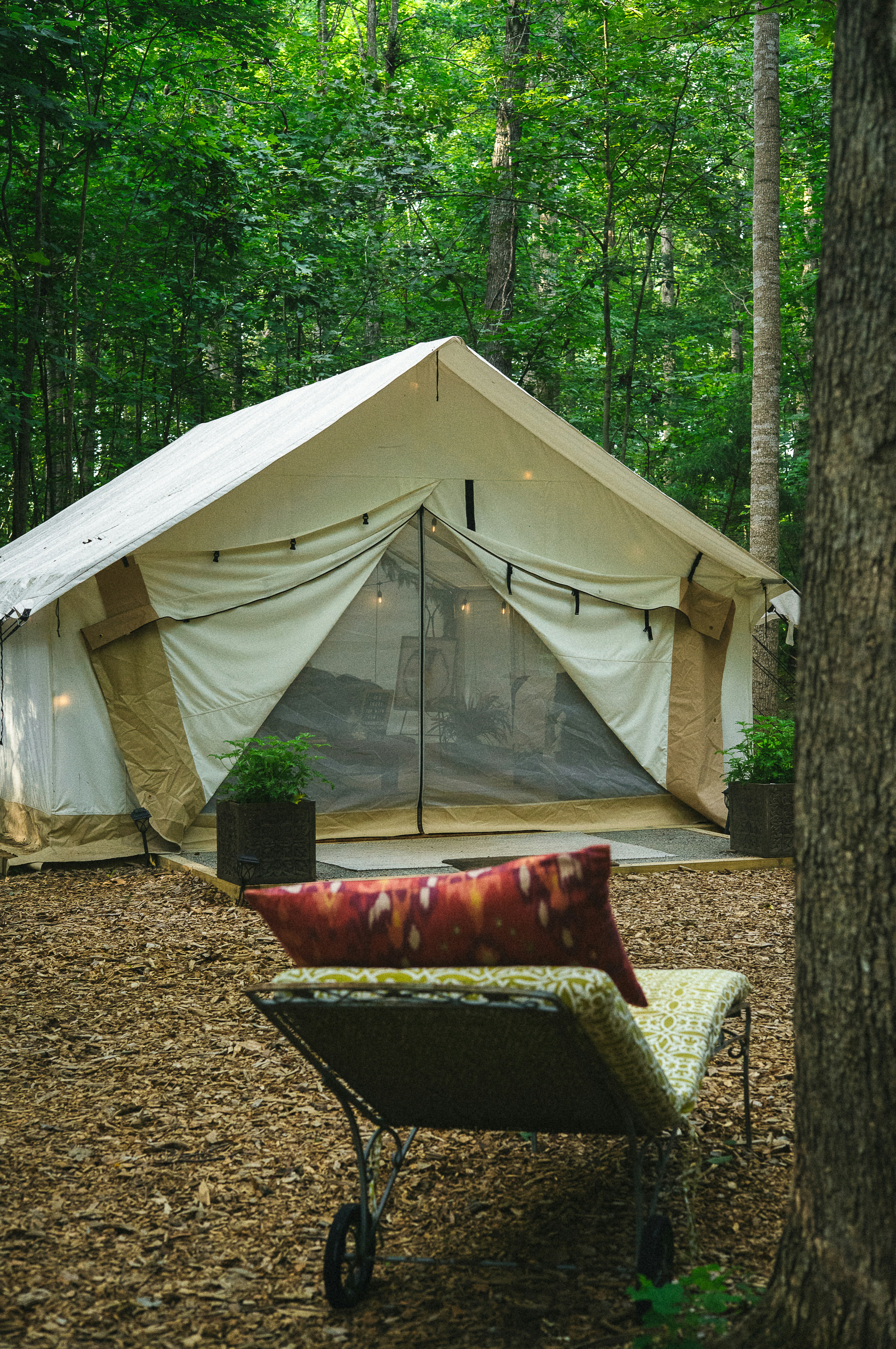 a red couch in front of a tent in the woods