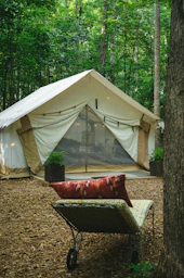 a red couch in front of a tent in the woods