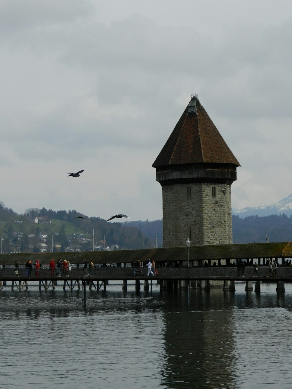 a group of people on a pier with Kapellbrücke in the background