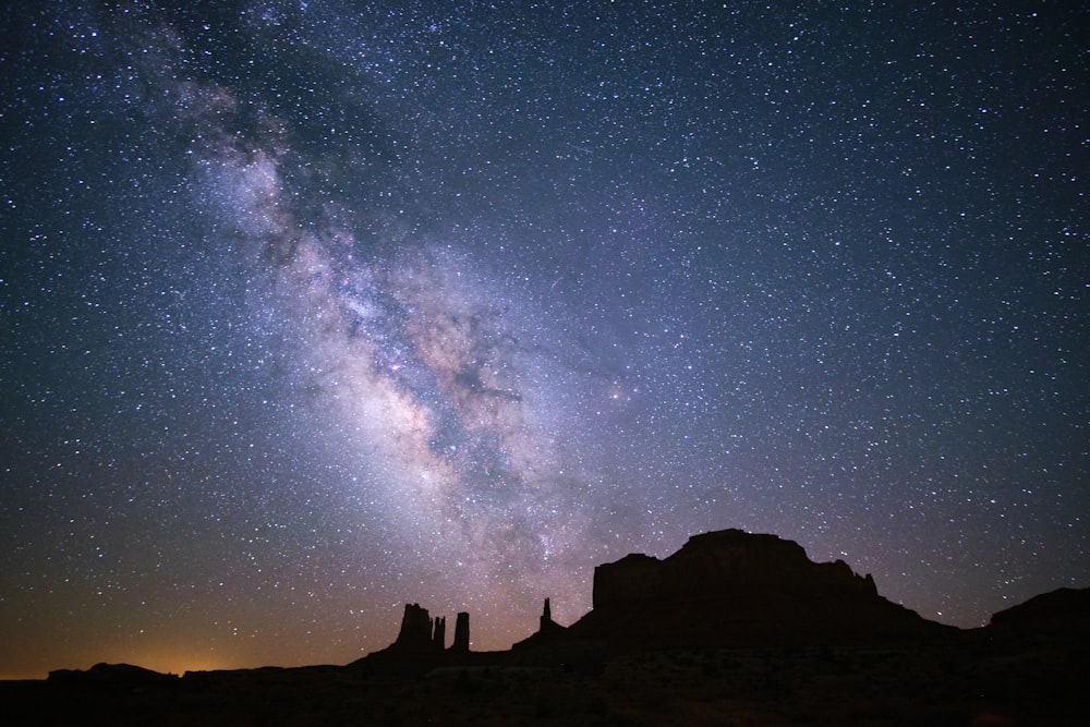 a starry night sky over a rocky mountain