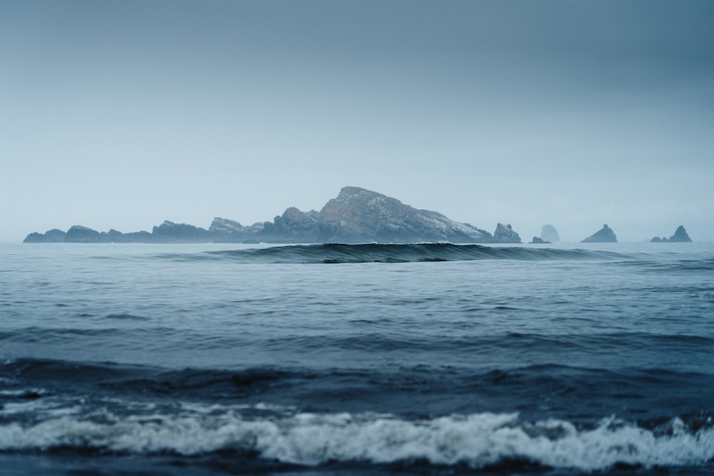 a body of water with a group of large rocks in the distance