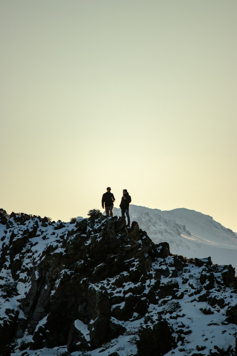 a couple of people standing on a snowy mountain