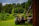 A smiling farmer standing next to his agriculture truck in a lush green field.