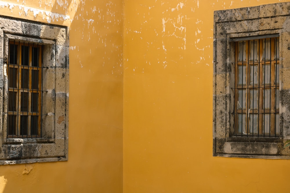 a couple of windows on a yellow wall