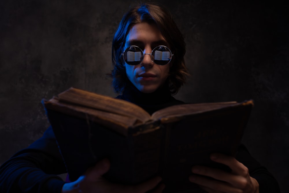 a girl wearing sunglasses and reading a book