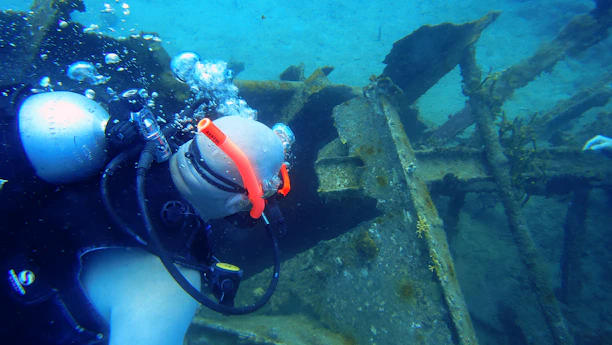 Professional diver carefully cleaning a ship's hull underwater with specialized equipment.