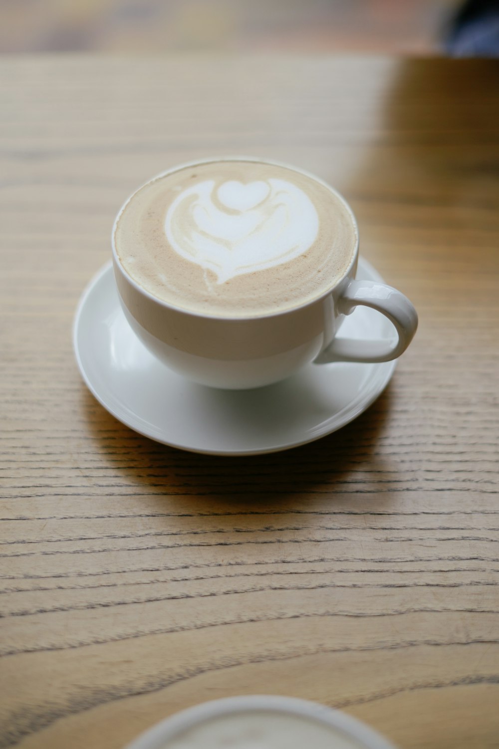 a white cup with a white foamy substance on a wooden surface