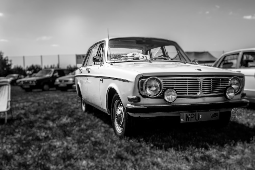 a black and white photo of a car parked on grass