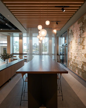 Close-up of a rustic wooden table with metal legs, surrounded by industrial pendant lights hanging from a concrete ceiling.