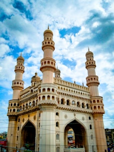 a large white building with towers with Charminar in the background