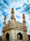 a large white building with towers with Charminar in the background