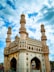 a large white building with towers with Charminar in the background